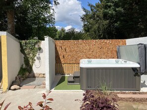 A backyard with a hot tub, a wooden fence, and a stone wall. - Le Parc du Séquoia : stay in a former apiary (Ostheim)