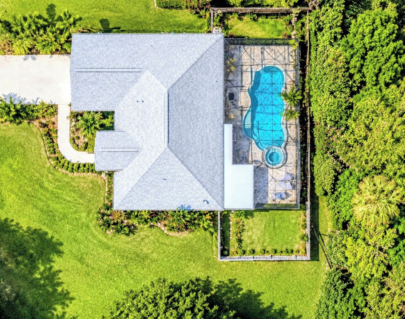 Vista aérea de una casa con piscina, rodeada de exuberante vegetación.