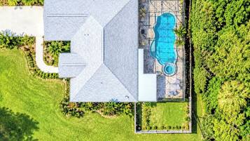 Vista aérea de una casa con piscina, rodeada de exuberante vegetación.