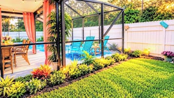 Un patio techado con piscina, mobiliario exterior y un césped bien cuidado.