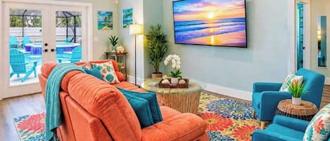 Ein Wohnzimmer mit einer Couch, Sesseln, einem Fernseher und Blick auf einen Pool.