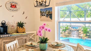Comedor con una mesa redonda, sillas y vista a una piscina y cascada.