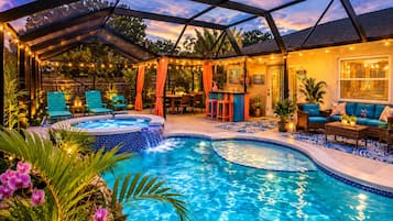 Un área de piscina con jacuzzi, mobiliario exterior y un patio cubierto.