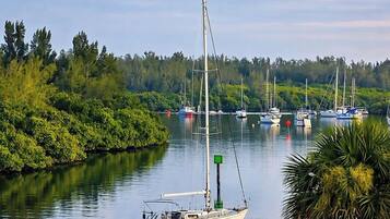 Ein ruhiger Hafen mit einem Segelboot, das an der Küste liegt, umgeben von üppigem Grün und weiteren Booten.
