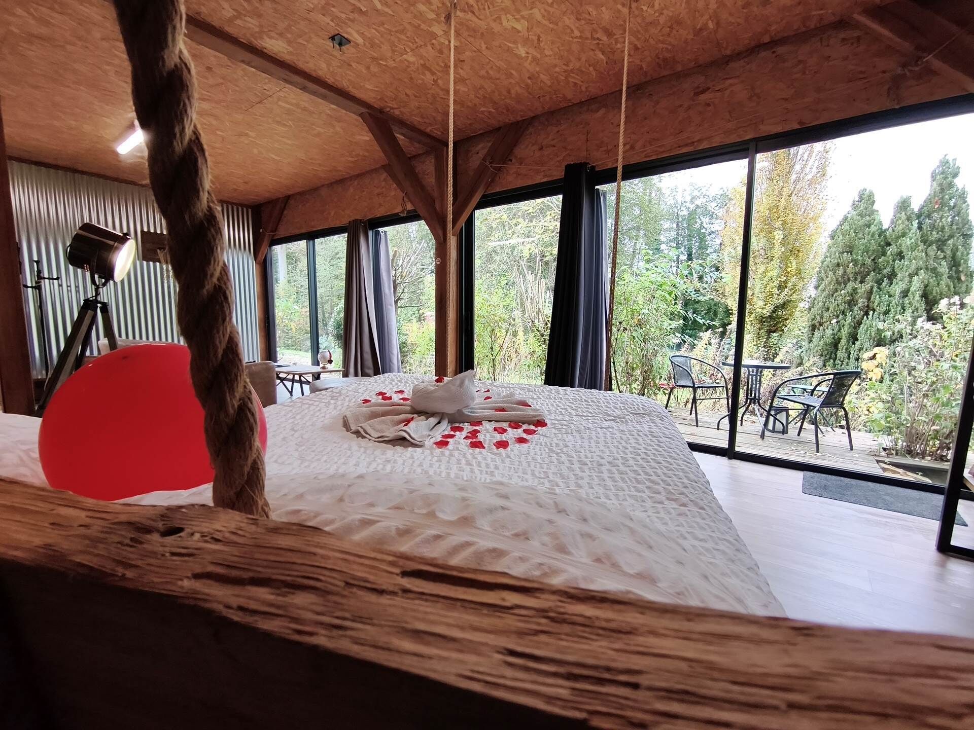Un dormitorio con una cama grande, techo de madera y vistas al exterior.
