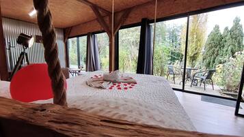 Un dormitorio con una cama grande, techo de madera y vistas al exterior.