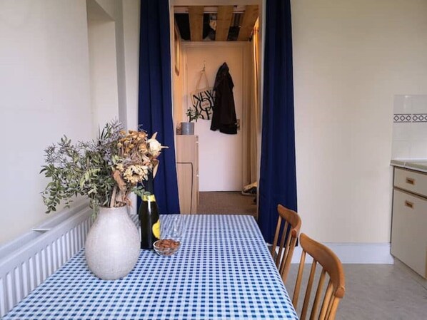 A dining area with a checkered tablecloth, a vase with dried flowers, and a wooden chair.