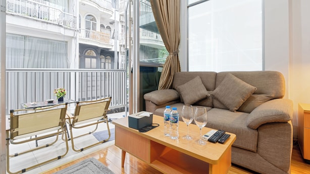 Una sala moderna con un sofá, una mesa de centro y un balcón que ofrece vistas a un edificio.
