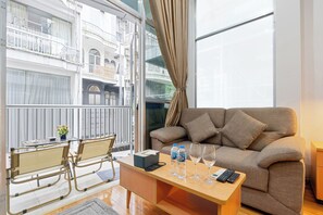 A modern living room with a sofa, a coffee table, and a balcony with a view of a building. - Wa Garden Sai Gon (Ho Chi Minh City)