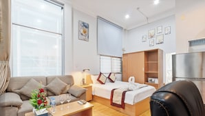 Una habitación de hotel moderna con sofá, cama, escritorio de madera y armario.