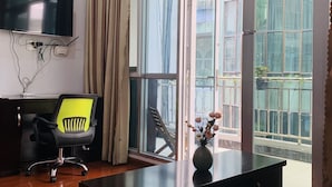 Un espacio de oficina moderno con un ventanal grande, un televisor de pantalla plana, un aire acondicionado y un escritorio con una silla.