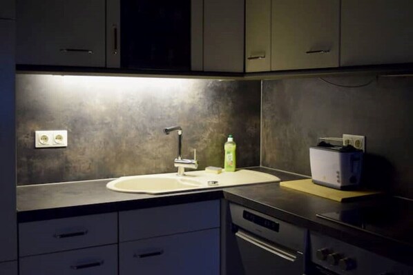 A modern kitchen with a stainless steel sink, a built-in oven, and a toaster on the countertop.