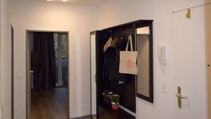 Un couloir avec une armoire, un miroir et une porte donnant sur une autre pièce.