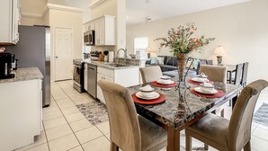A modern kitchen with white cabinets, a dining area with a marble table, and a ceiling fan. - Glenbrook Vacation Pool/Spa Home Near Disney (Clermont)