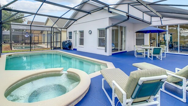 An indoor swimming pool with lounge chairs and a covered patio area. - Glenbrook Vacation Pool/Spa Home Near Disney (Clermont)