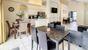 A spacious living area with a dining table, sofas, and a kitchen in the background. - Glenbrook Vacation Pool/Spa Home Near Disney (Clermont)