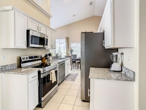 A modern kitchen with white cabinets, stainless steel appliances, and a granite countertop.