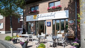 A hotel restaurant with outdoor seating, flower planters, and a signboard. - Hotel Schwanenhof (Erkelenz)