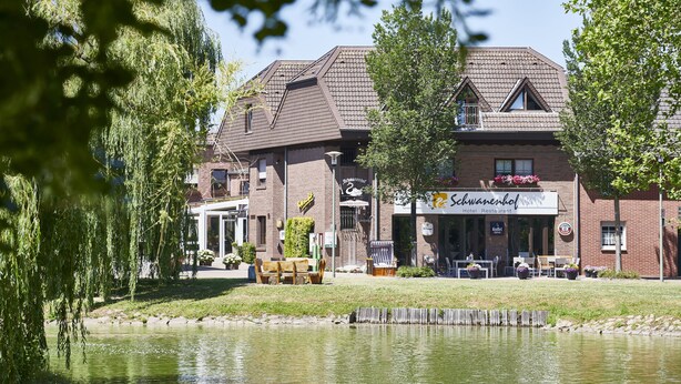 A hotel with a restaurant on the ground floor, outdoor seating, and a pond in front. - Hotel Schwanenhof (Erkelenz)