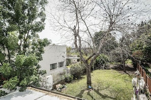 Zona residencial con un edificio blanco, un árbol y un patio cubierto de césped.