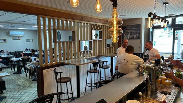 A bar area with a counter, stools, and a bartender. - LE RELAIS SAINT GERMAIN (Saint-Germain)