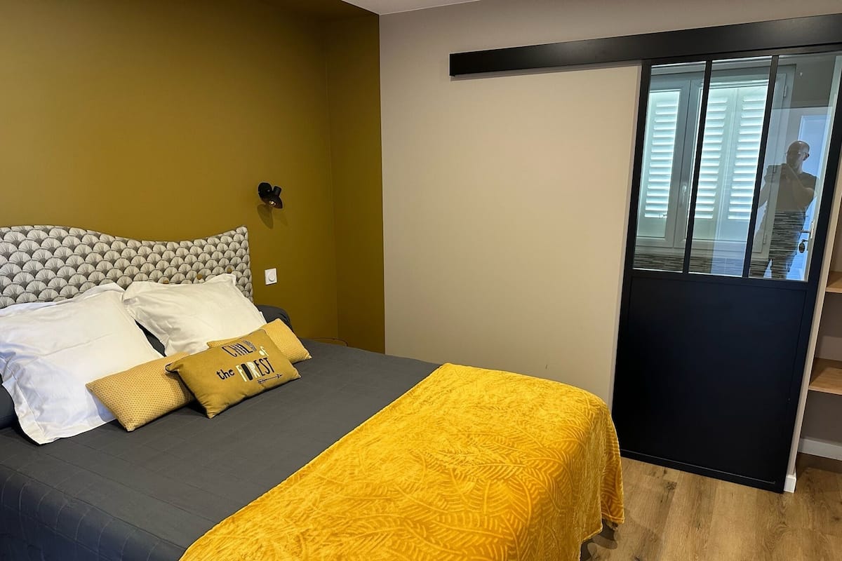 A bedroom with a bed, a yellow bedspread, and a headboard with a patterned design.