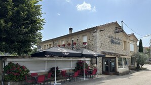 A stone building with a bar and restaurant area, outdoor seating with umbrellas, and a visible entrance. - LE RELAIS SAINT GERMAIN (Saint-Germain)