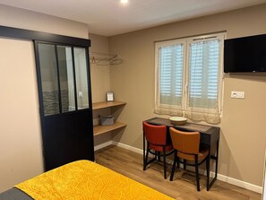 Cozy retreat with a bed, desk, and TV, offering a view of the outdoors.