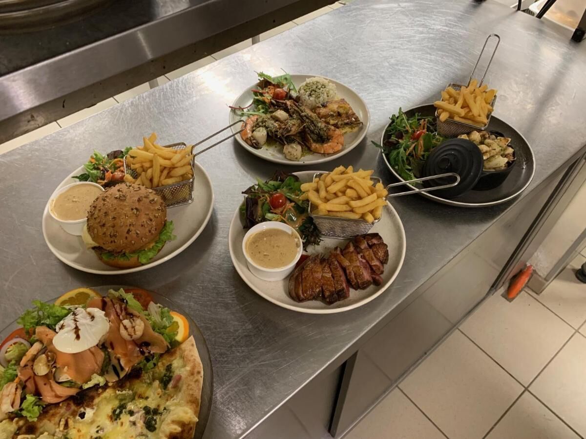 A buffet table with various dishes including burgers, salads, and grilled meats.