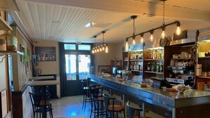A bar area with a long counter, stools, and hanging light fixtures. - LE RELAIS SAINT GERMAIN (Saint-Germain)