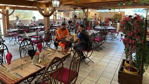 An outdoor dining area with wooden tables and chairs, surrounded by greenery and decorative lights. - LE RELAIS SAINT GERMAIN (Saint-Germain)