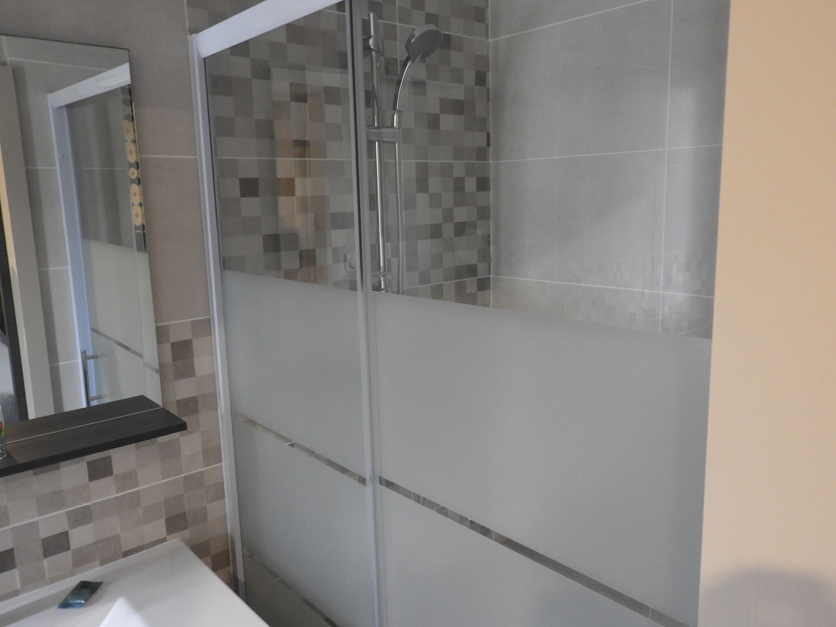 Une salle de bain moderne avec une douche à parois de verre, un lavabo blanc et un miroir.