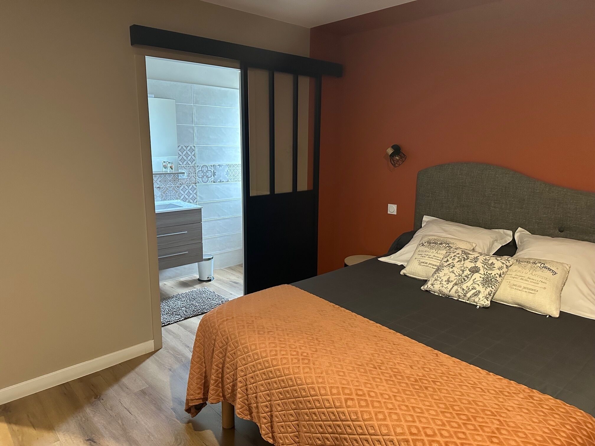 A bedroom with a bed, a dresser, and a bathroom visible through an open door.
