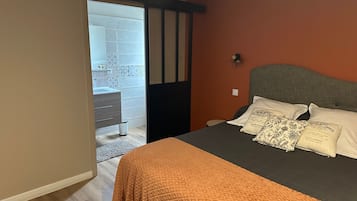 A bedroom with a bed, a dresser, and a bathroom visible through an open door.