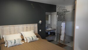 A bedroom with a bed, pillows, a bedside table, a mirror, and a bathroom with a shower and sink. - LE RELAIS SAINT GERMAIN (Saint-Germain)