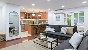 Een moderne woonkamer met een bank, salontafel en een keuken op de achtergrond.