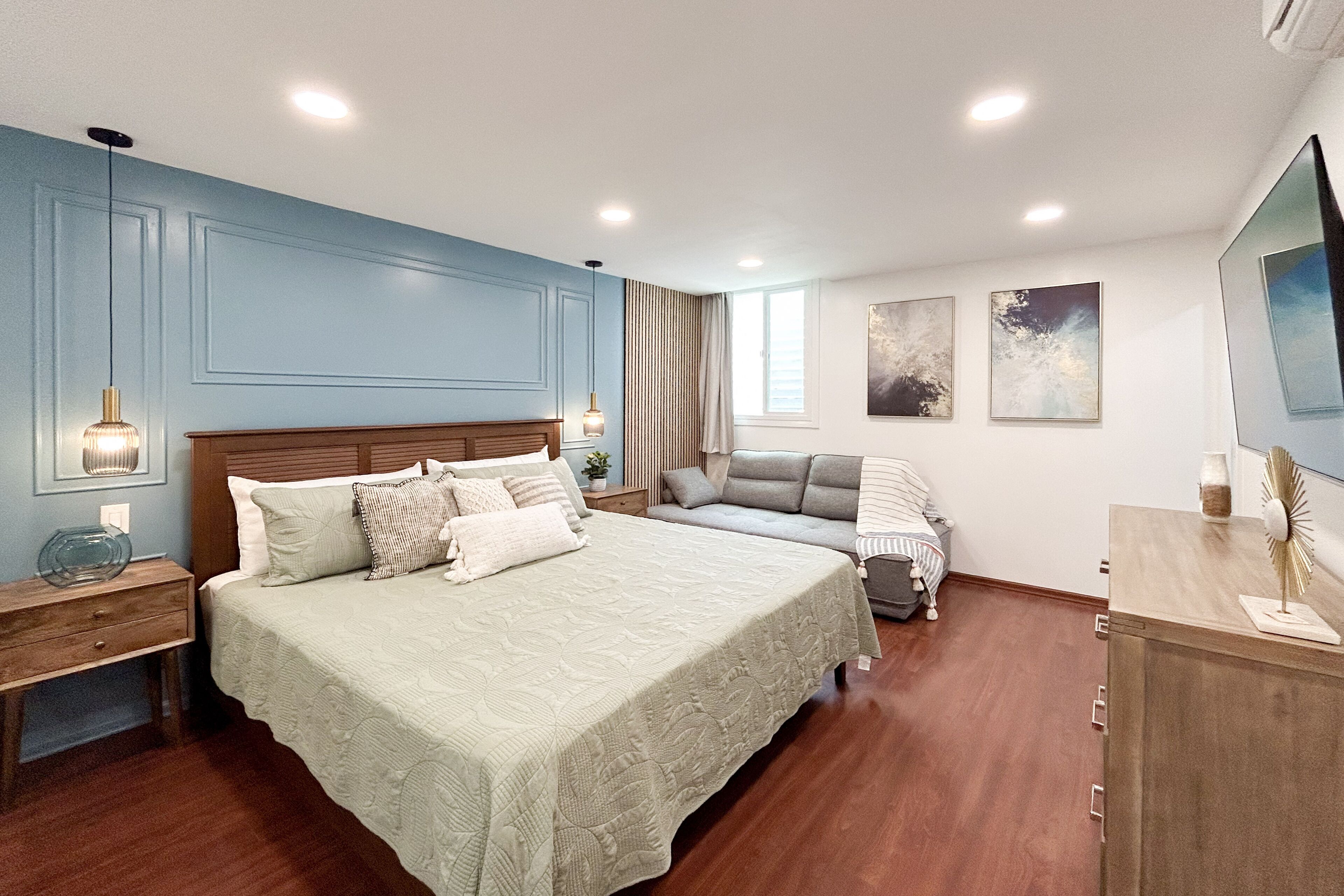 A bedroom with a large bed, a sofa, a desk, and a TV.