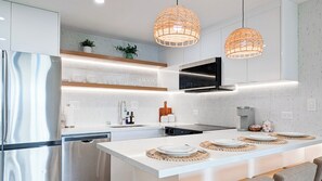 A modern kitchen with a stainless steel refrigerator, a built-in oven, and a large island with a dining setup.