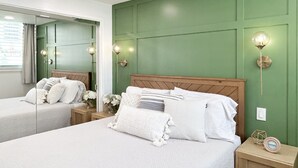 Een hotelkamer met twee bedden, groene wanden en wandlampen.