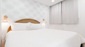 A bedroom with a large bed, a wooden headboard, two wall-mounted lamps, and a window with curtains.