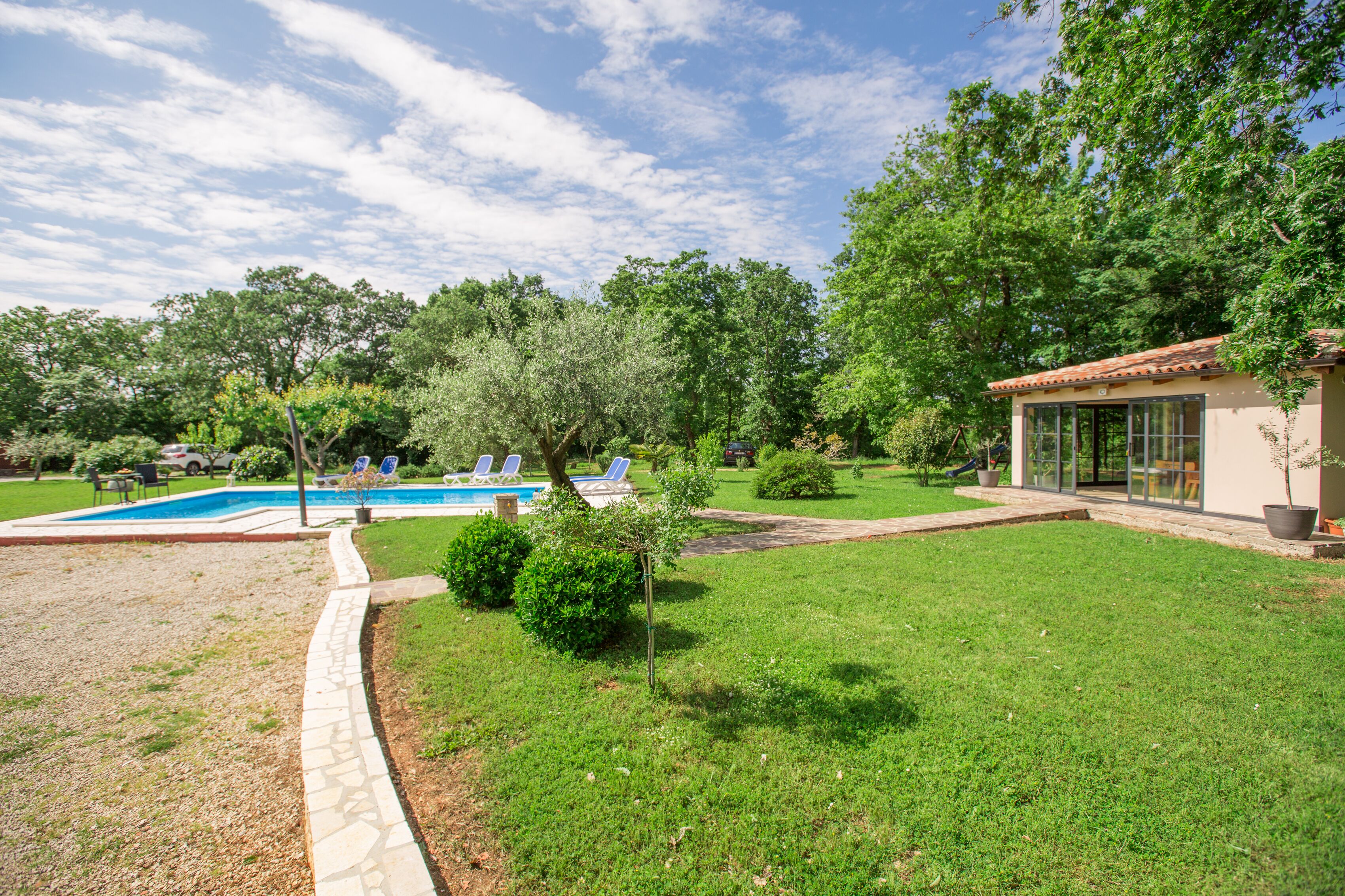 Un pati amb piscina, una construcció petita i un jardí ben cuidat.