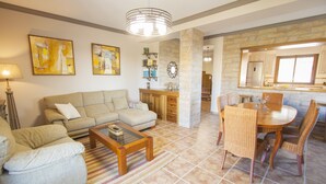 A living room with a sofa, coffee table, and dining area with chairs and a table.