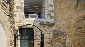 A stone building with a gated entrance and a small balcony.