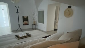 A bedroom with a large bed, a bedside table, a floor lamp, and a wall-mounted hat.
