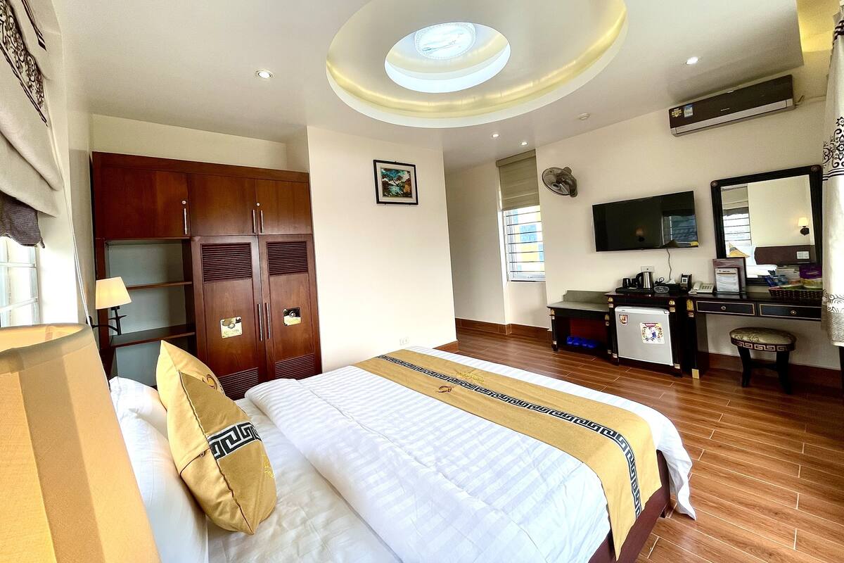 Habitación de hotel con cama, armario, escritorio y una lámpara en el techo.