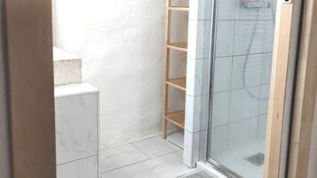 Een moderne badkamer met een douche met glazen wand, een houten plankunit en marmeren vloeren.