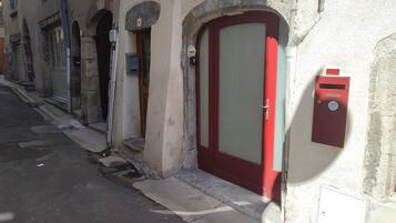Une rue étroite avec une porte rouge et une boîte aux lettres sur le côté droit.