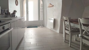 A kitchen with white cabinets, a sink, and a window. There is a wooden coat rack and a white radiator. - Les Insolites de Champeix 3 (Champeix)