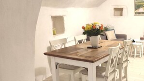 A dining area with a wooden table and white chairs, a vase with flowers, and a framed picture on the wall. - Les Insolites de Champeix 3 (Champeix)