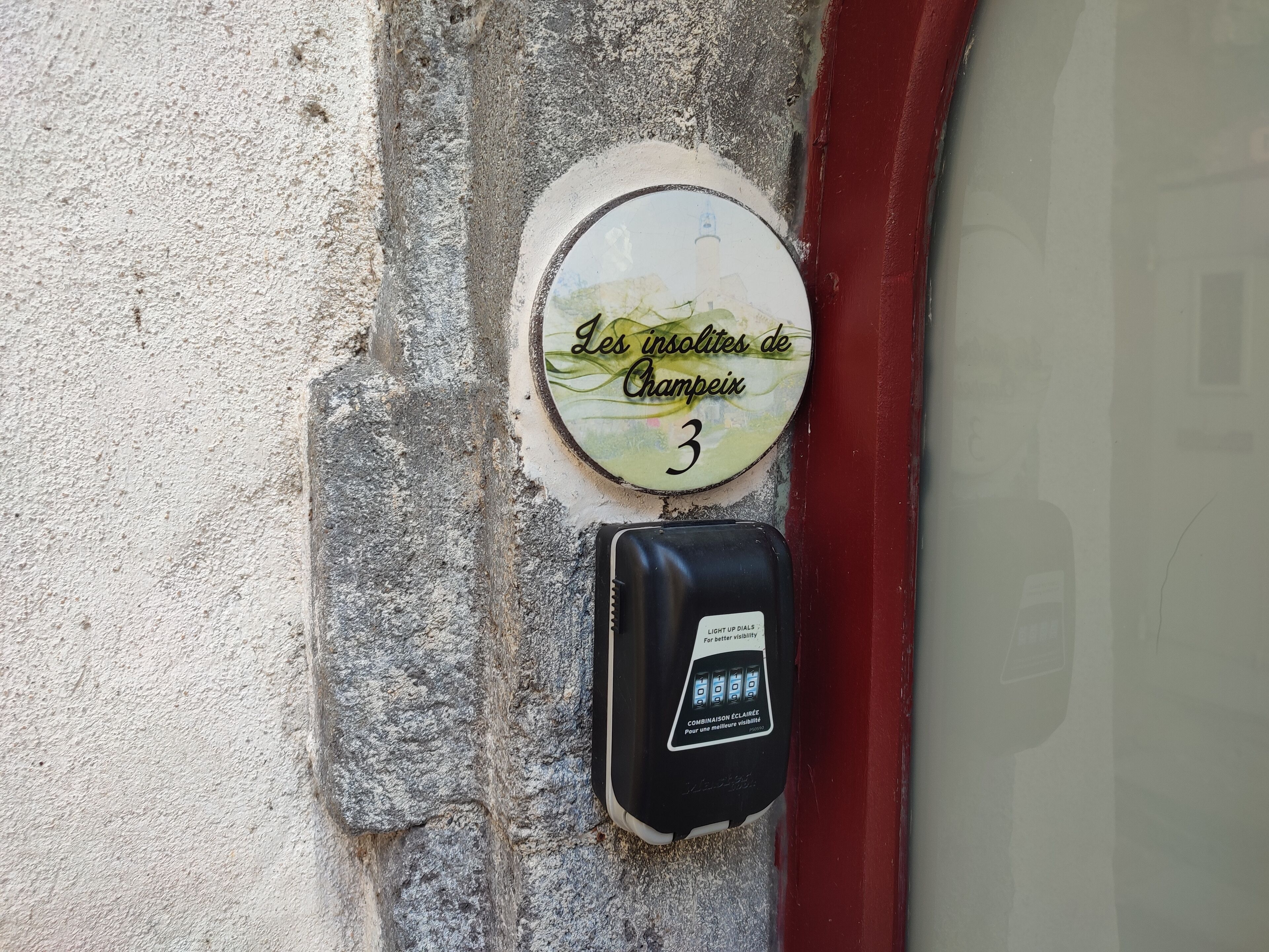 A wall-mounted sign with the text "Les isolites de Champeix 3" and a security device below it.